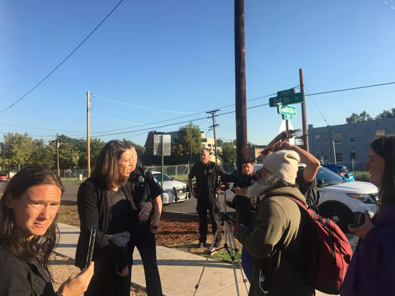 Image: An inspector from Denver Public Health and Environment explains to people living in the encampment that she will perform an inspection.