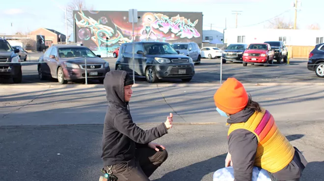 A mirroring game is played by two people in a parking lot.