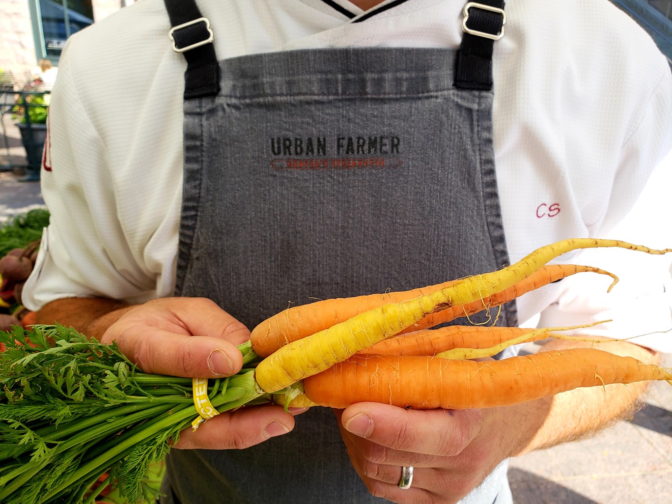 Chef Chris Starkus of Urban Farmer holds colorful carrots from ACRES at Warren Tech.