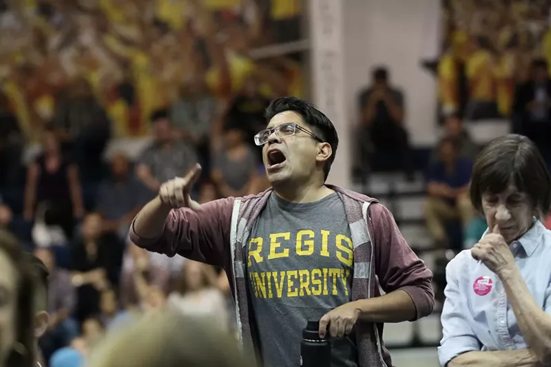 Image: An audience member was led off by police after heckling Senator Cory Gardner.