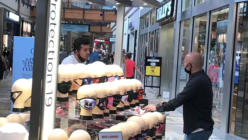 Image: Yes, this is a photo of two people at a FlatIron Crossing mask kiosk wearing masks incorrectly.