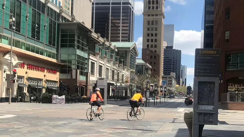 Image: Unmasked cyclists roll down a nearly deserted section of the 16th Street Mall on May 9.