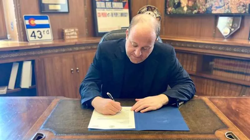 Image: Governor Jared Polis writing a letter to the Small Business Administration "for federal funding in order to provide relief for Colorado's small businesses dealing with the impacts of COVID-19."