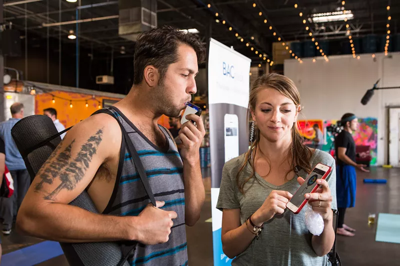 Image: A man tests out a breathalyzer at a CDOT event