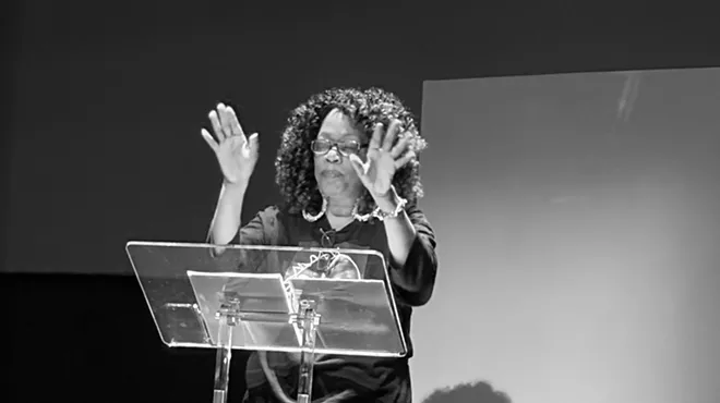 A Black woman stands behind a podium.