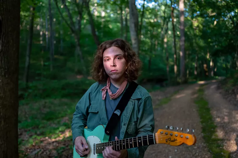 Image: man holding a guitar outside