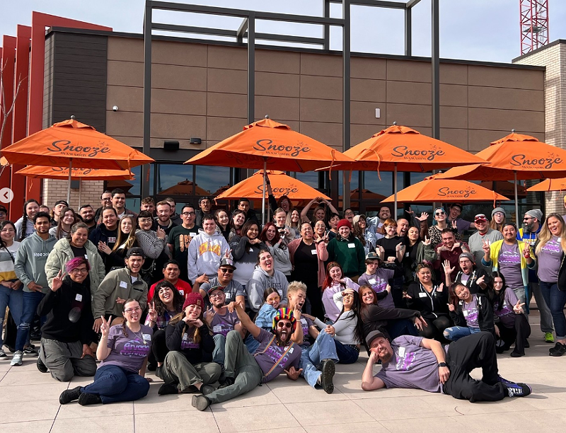 Image: a large group of people in front of orange umbrellas