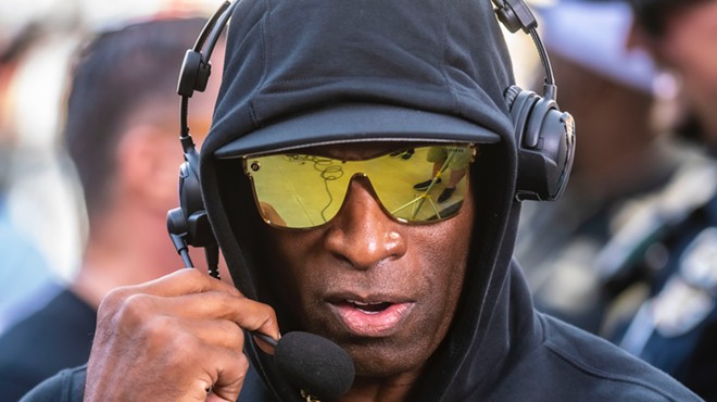 A man in reflective sunglasses speaks into a headset.