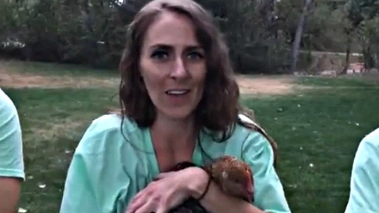 A screen capture from a Facebook video showing a member of Denver Baby Animal Save posing with a chicken said to have been rescued during a weekend action.