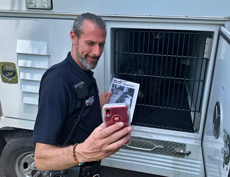 Image: Daniel Ettinger takes a selfie with a poster of a blind dog that was lost and found.