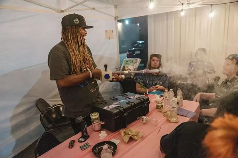 Image: A man blows smoke with a device.