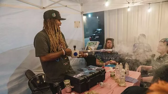 A man blows smoke with a device.