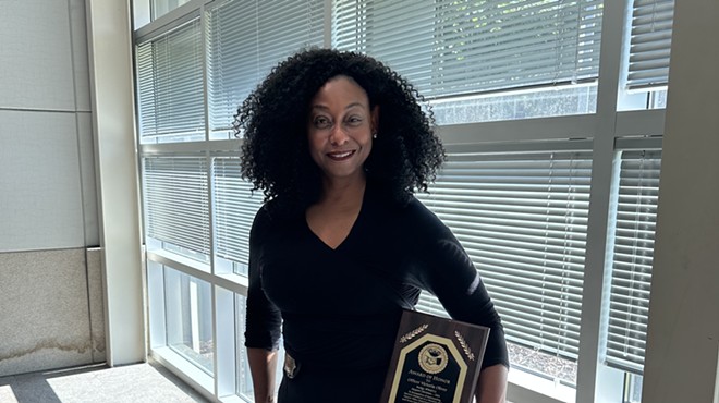 Officer Victoria Oliver standing with her Citizens Appreciate Police (CAP) award that she received for buying a plane ticket for a woman to escape domestic violence.
