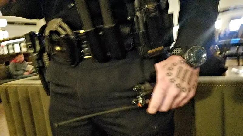 Image: A photo of Officer Michael Traudt shows a tattoo on his hand whose design duplicates the logo of an anti-government militia group, but he says he was never a member of the organization.