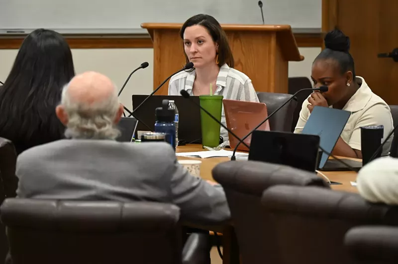 Image: A woman listens at a conference.