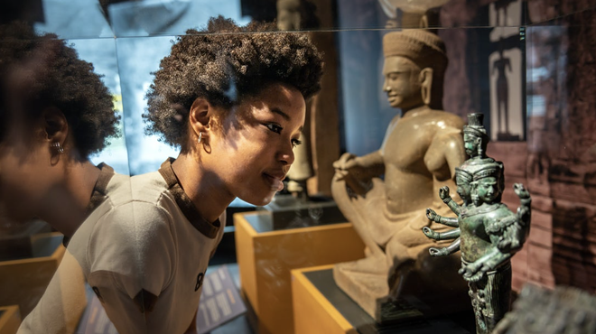 A boy looks at a small statue