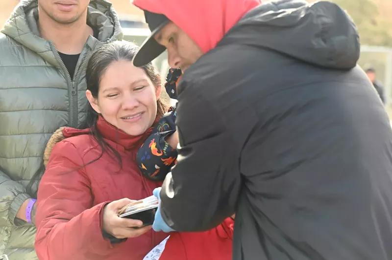 Image: A migrant takes a packaged meal from SAME Cafe.