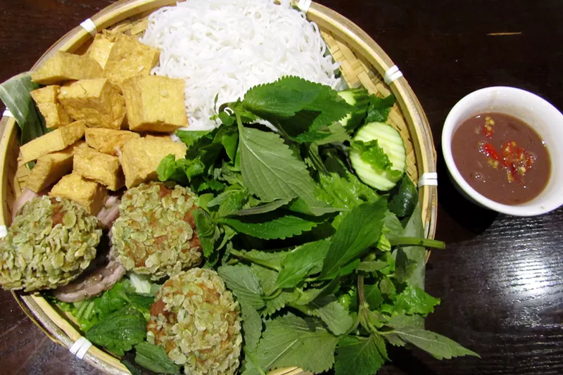 Image: Fresh herbs, tofu, pork sausage coated in fried green rice and a pile of noodles make up bun dau mam tom, but the pungent sauce is the star.