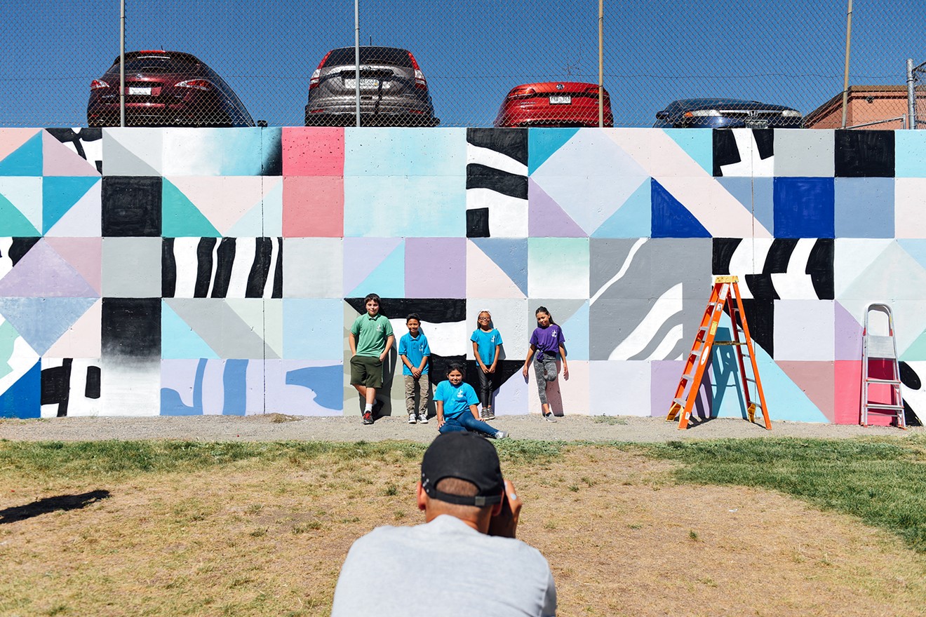 International artist Saïd Kinos takes a photo of Nicholas (left), Nico, Nivia, Timberly and Christine in front of a mural he painted with their help on Friday, September 15, at Cowell Elementary School.