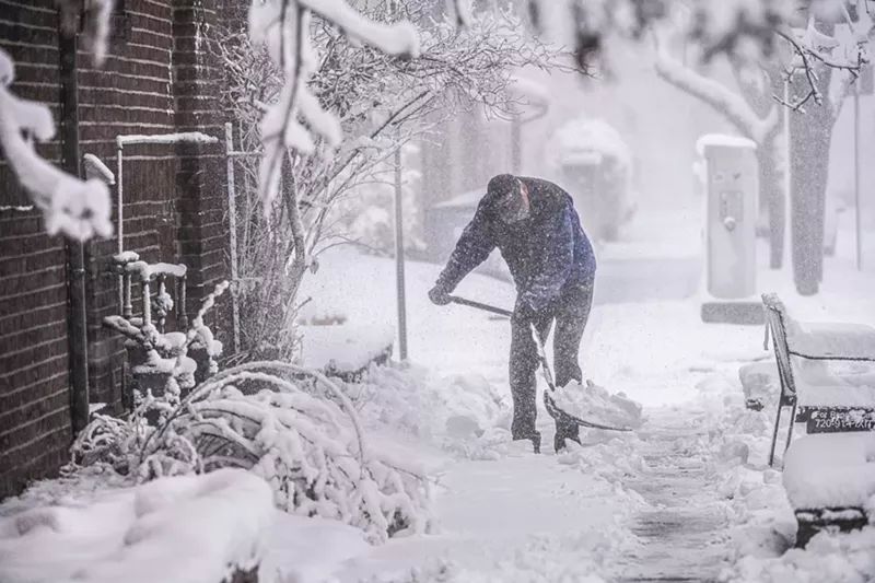 Image: Man shovels snow on the sidewalk in Denver