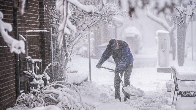 Man shovels snow on the sidewalk in Denver