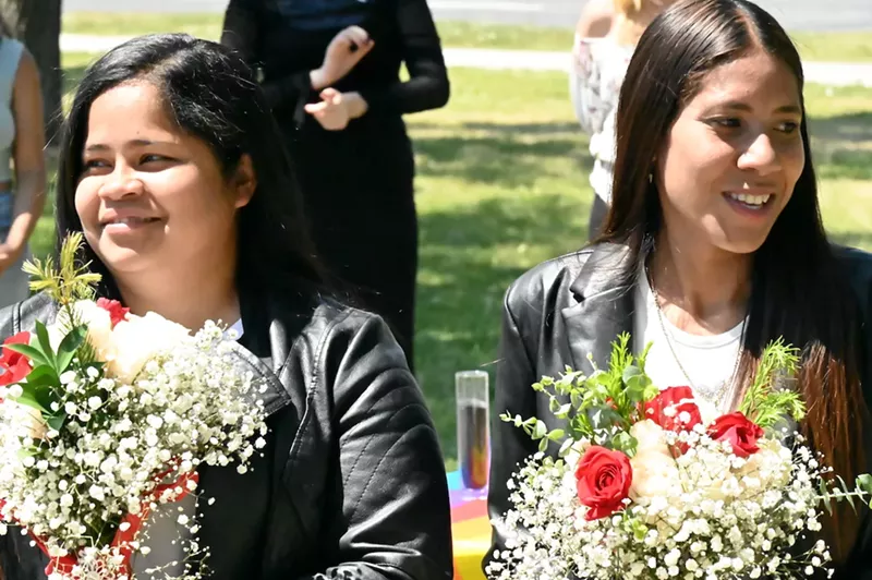 Image: Two women hold flowers.