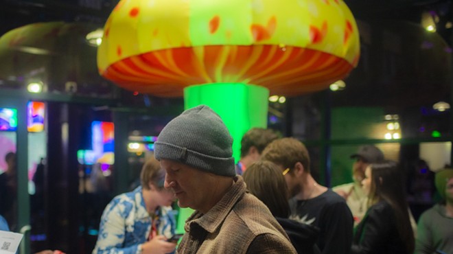 Man in a beanie stands in front of inflatable giant mushroom