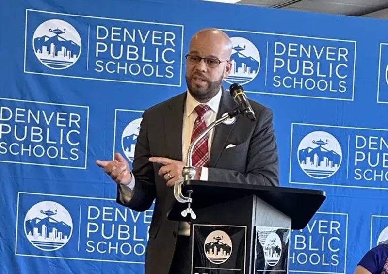 Image: man at podium with school signs in background