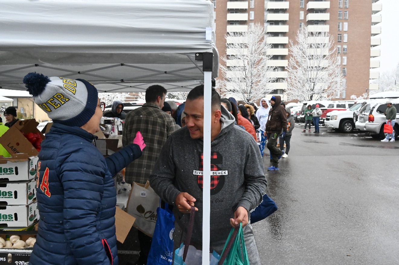 Migrants line up to receive food donations from the LoVVe Project on Saturday, April 20.
