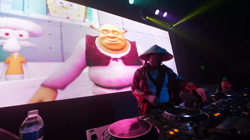Image: man deejaying with image of shrek in the background