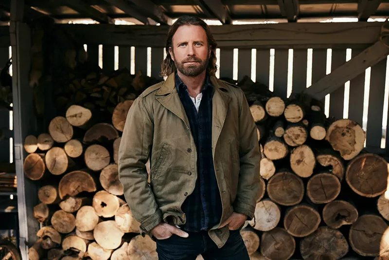 Image: man standing in front of logs