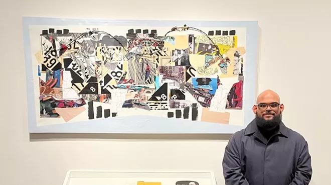 man standing next to his artwork