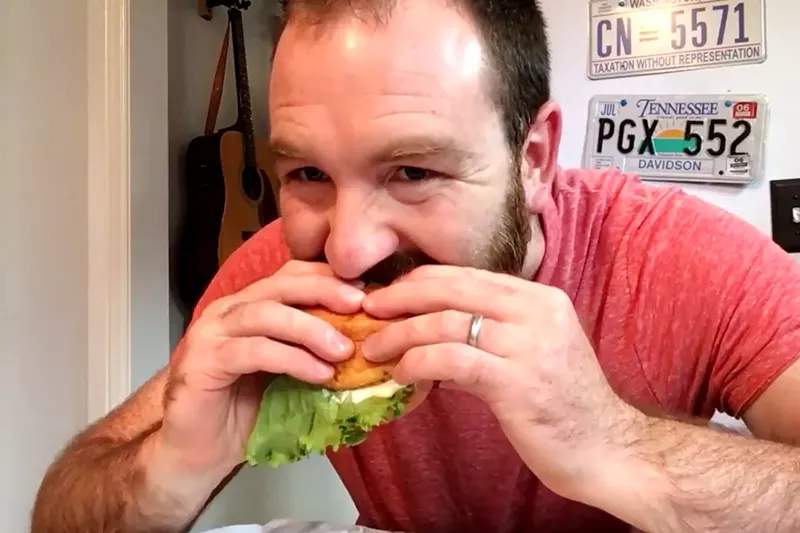 Image: Nick Evans takes a big bite out of a Smashburger burger — strictly for research purposes, of course.