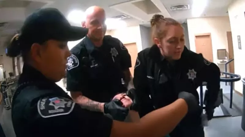 Image: Lauren Gotthelf grimacing while under restraint in Boulder County jail, as seen in a video on view below.
