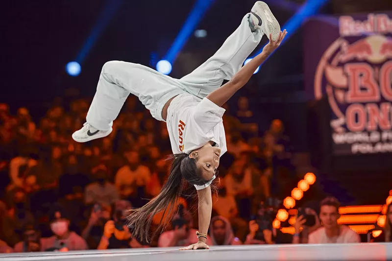 Image: A woman breakdances.