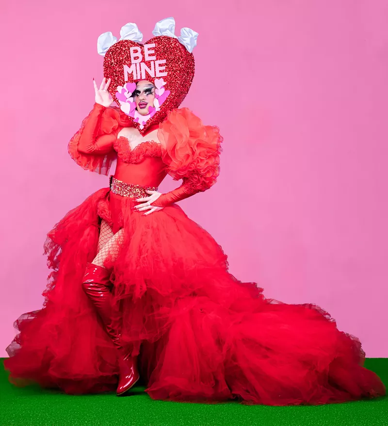 Image: A drag performer strikes a pose in red.