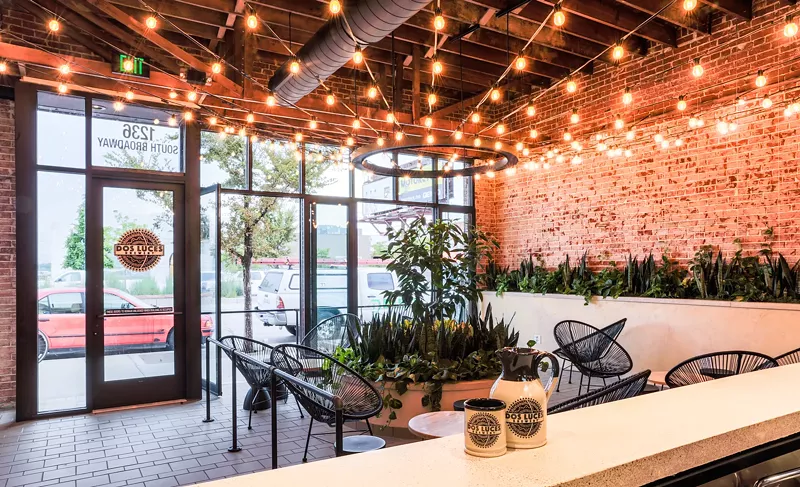 Image: a room with a brick wall, chairs and string lights on the ceiling