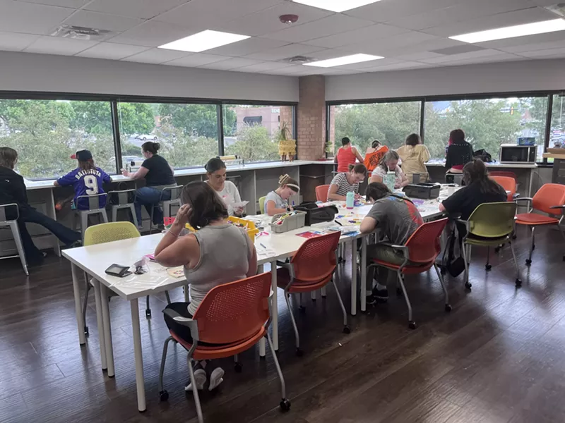 Image: People sit around a table working together to assemble Kynd Kits.