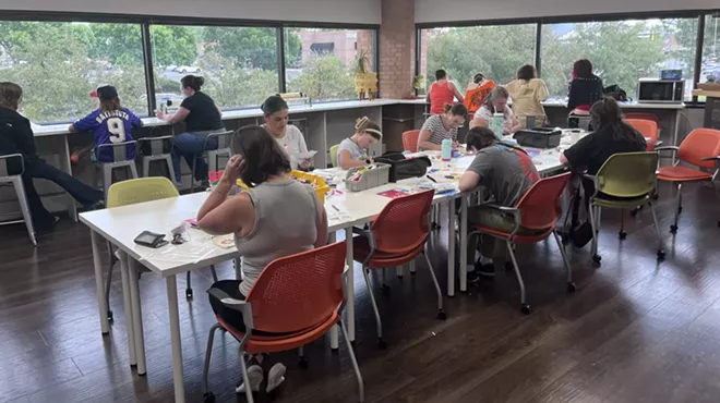 People sit around a table working together to assemble Kynd Kits.