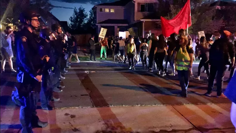 Image: Officers from the Aurora Police Department and protesters outside the home of Johnny Choate, warden of the GEO facility in Aurora.