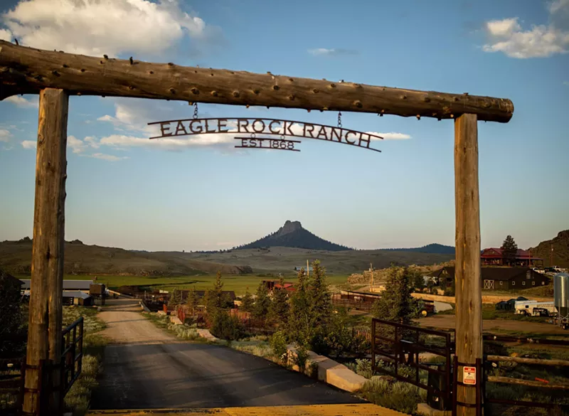 Image: wooden ranch entrance in front of a mountain view