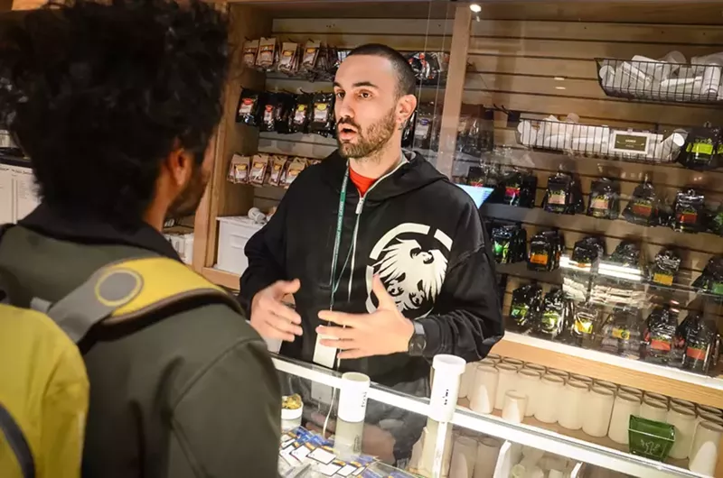 Image: Dispensary budtender assists customer with marijuana purchase