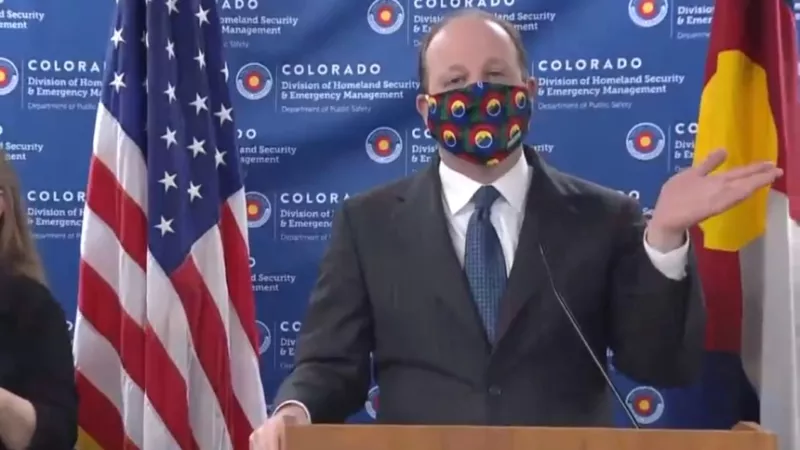 Image: Governor Jared Polis during an April 3, 2020, press conference during which he modeled a cloth mask for the first time.