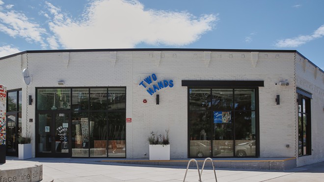 exterior of a white building with a blue sign that says "two hands"