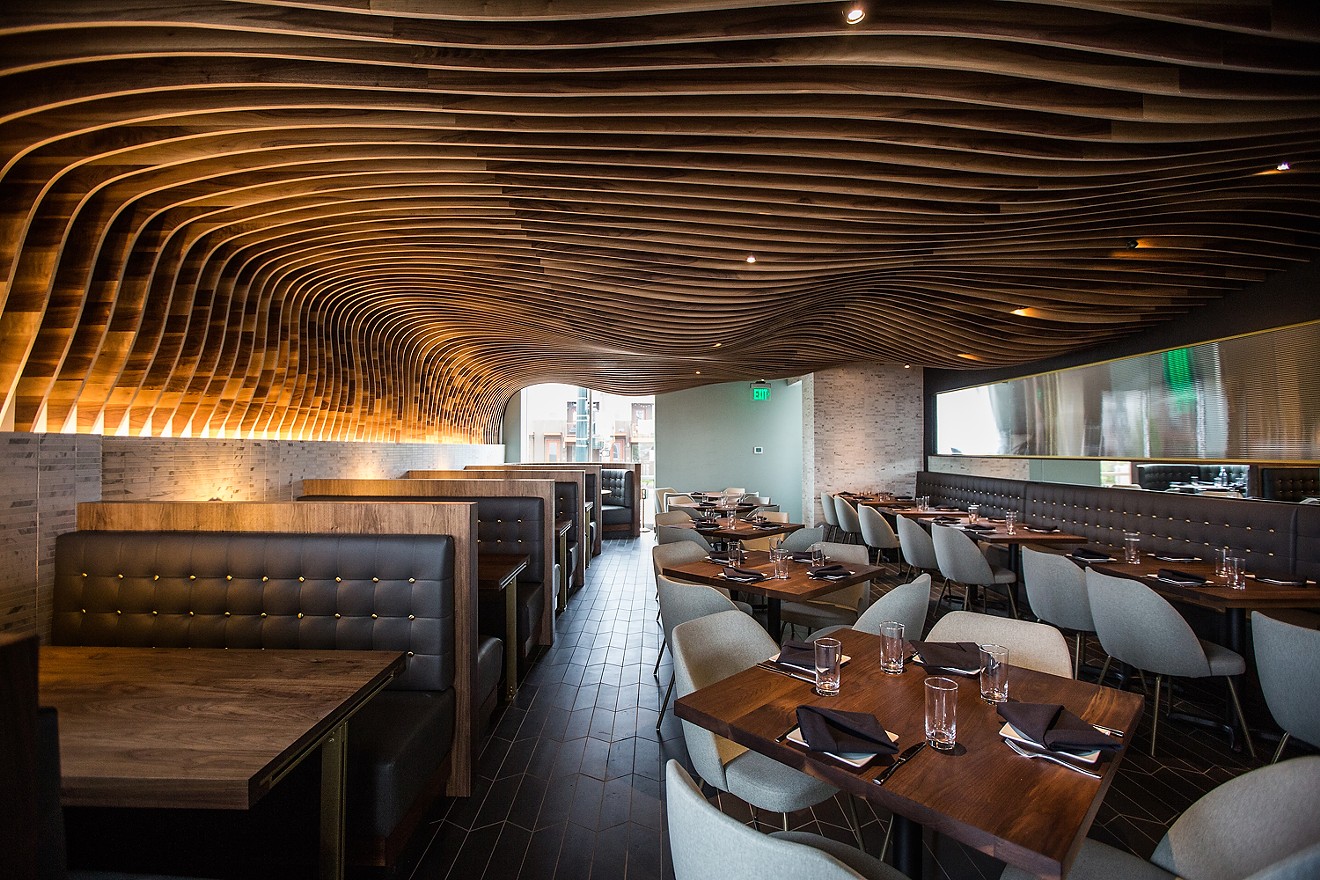 Rippling wood slats form a cavern-like ceiling over the dining room.
