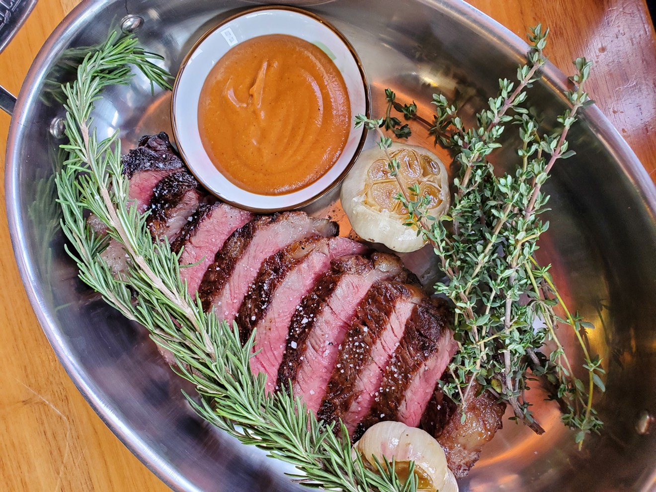 Steak is served with roasted garlic and fresh rosemary and thyme.