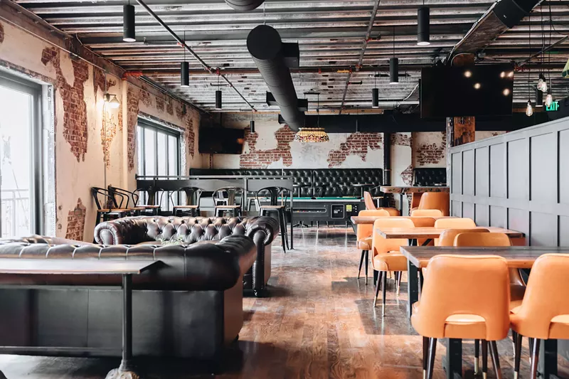 Image: a room with leather couches and tables with orange chairs