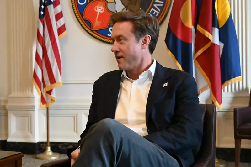 Image: Mayor Mike Johnston man sits next to American flag.
