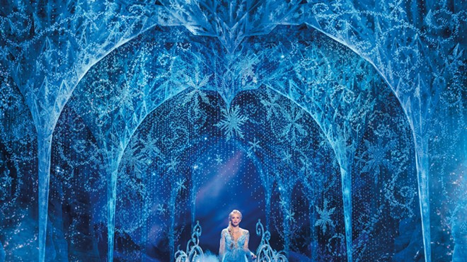 a woman in a blue dress on stage with ice decorations for Frozen production