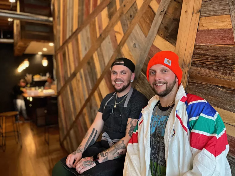 Image: Two men in beanies sit and smile